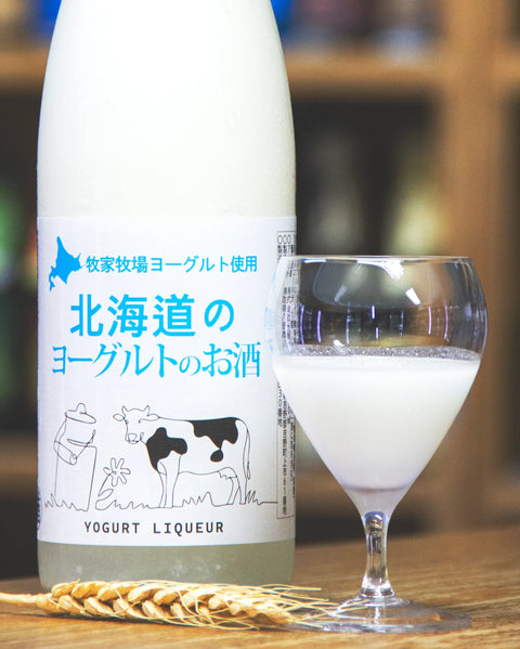 Bottle of yogurt liqueur with a glass filled with the product on a wooden surface.
