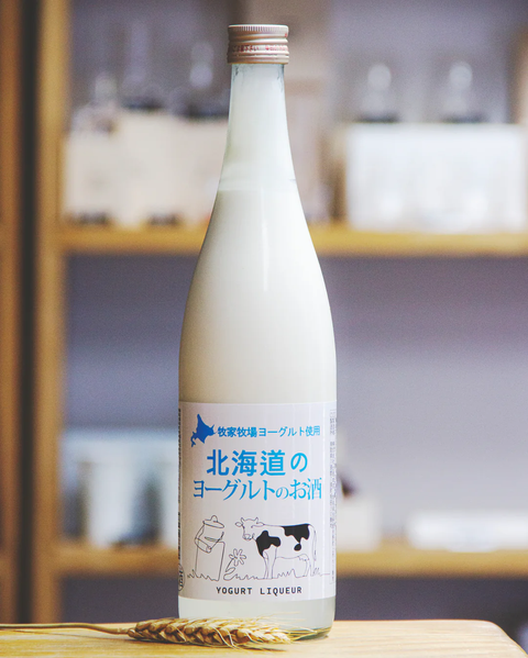 Bottle of hokkaido yogurt liqueur with a label featuring cows on a wooden surface.